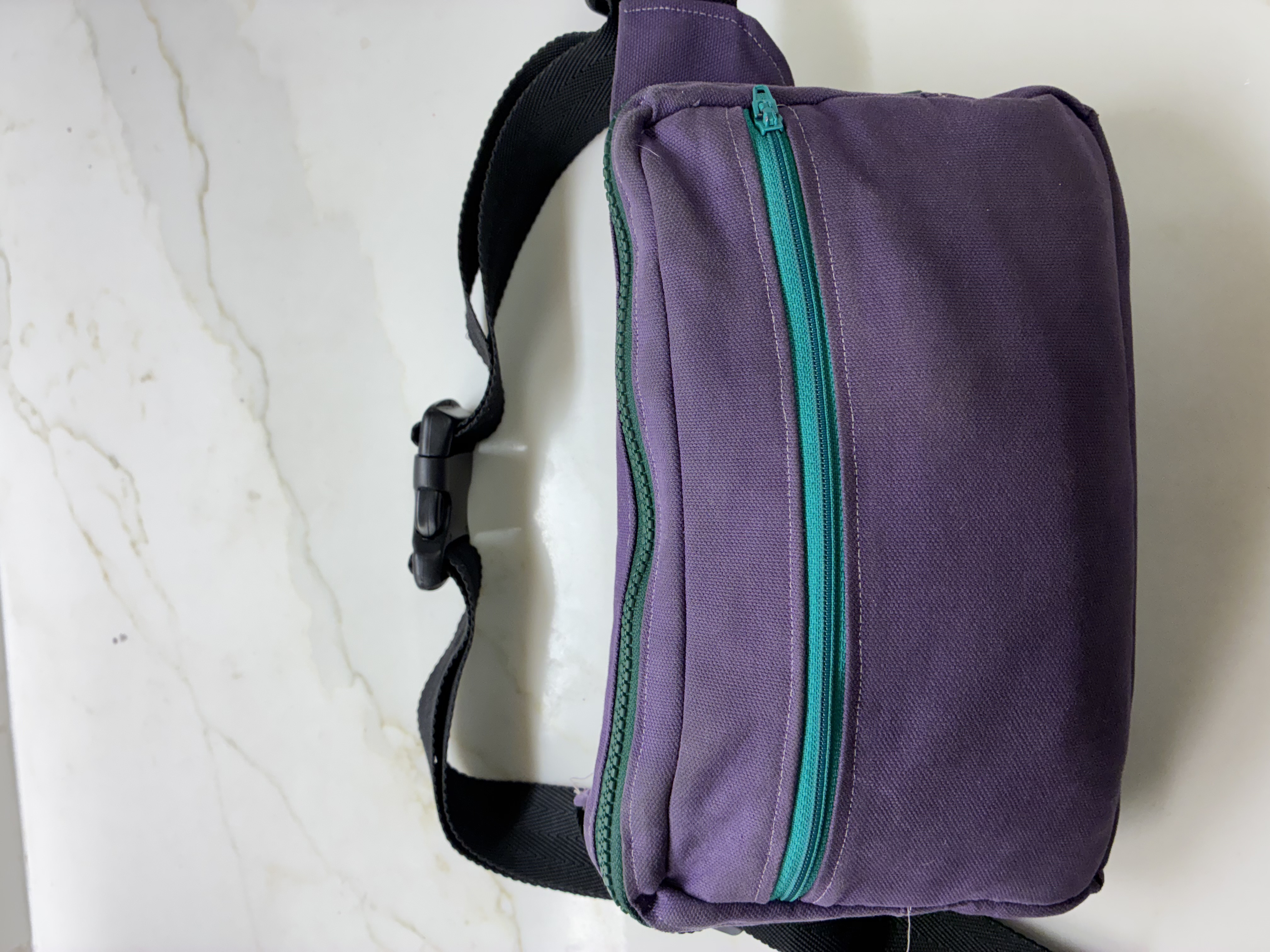 Purple fanny pack bag with a green zipper