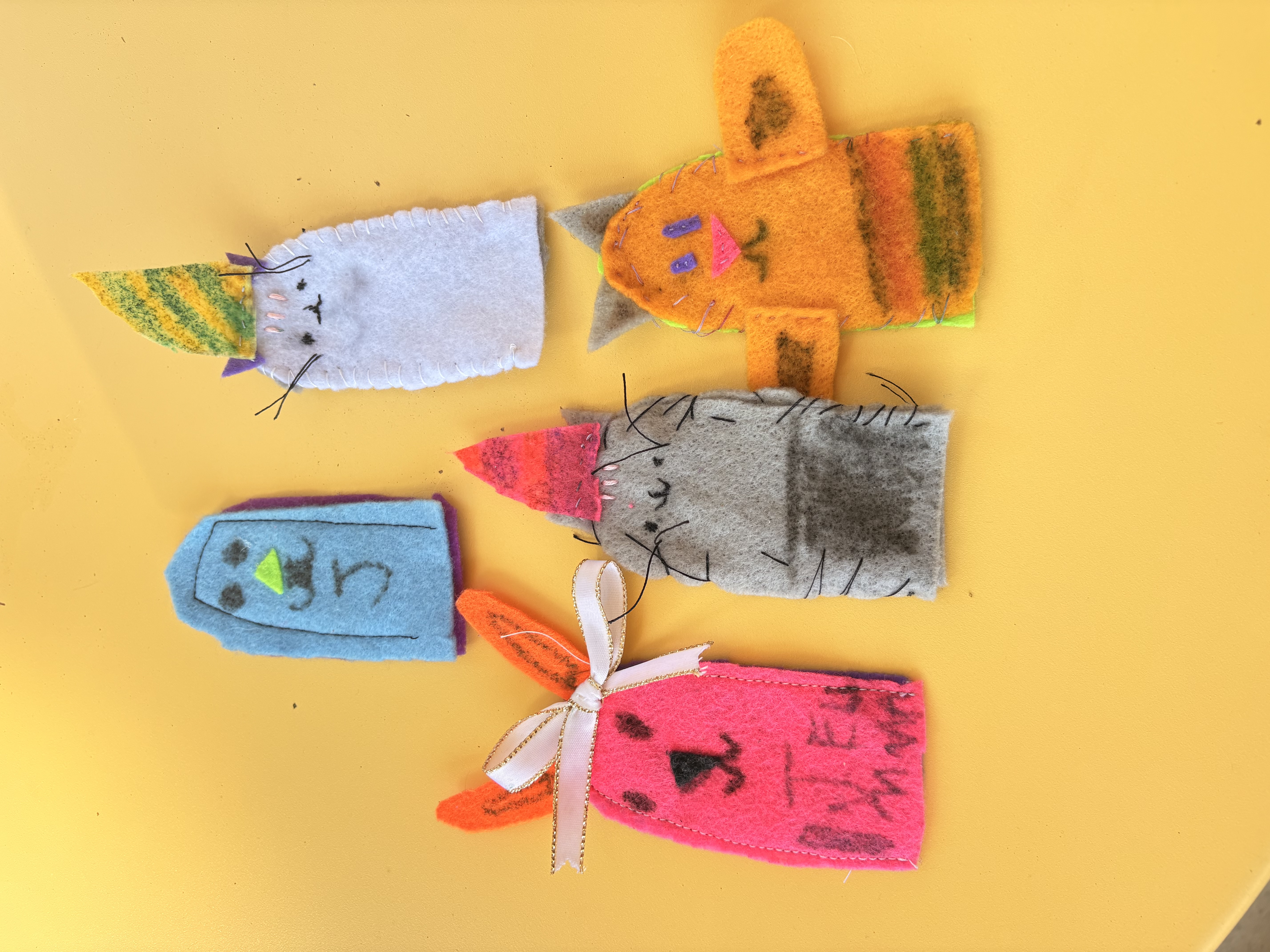 five colorful finger puppets on a yellow background